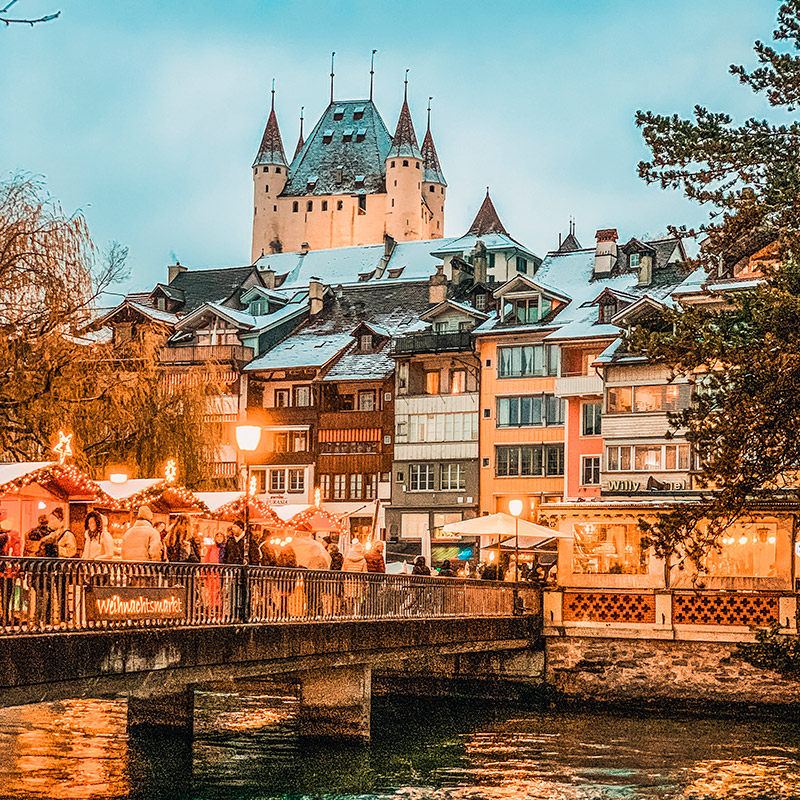 Weihnachtsmarkt in Thun mit festlich geschmückten Ständen und Lichterketten – Teil des Erlebnistrails Finding-Daniel für Gruppen und private Schnitzeljagden.