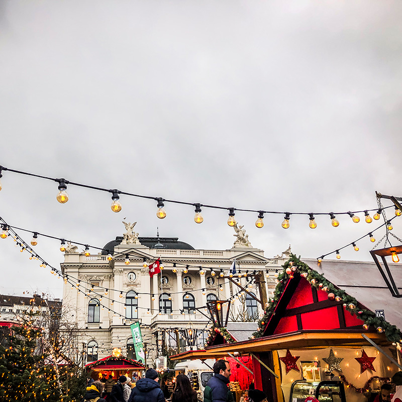 Weihnachtsmarkt in Zürich mit festlich geschmückten Ständen und Lichterketten – Teil des Erlebnistrails Finding-Daniel für Gruppen und private Schnitzeljagden.
