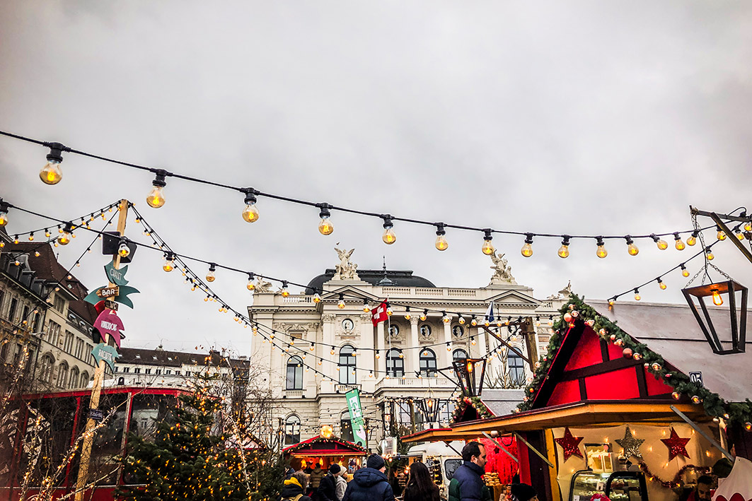 Weihnachtsmarkt in Zürich mit festlich geschmückten Ständen und Lichterketten – Teil des Erlebnistrails Finding-Daniel für Gruppen und private Schnitzeljagden.