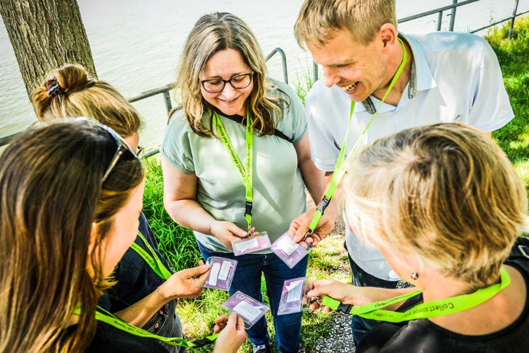 Gruppe von fünf Personen mit Teamkit-Umhängebändern posiert fröhlich im Kreis stehend.